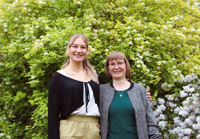 Zwei lächelnde Frauen (Team)vor einem grünen Baum